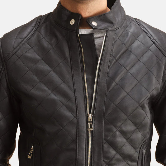 Front view of a man modeling a fully zipped black leather jacket, featuring diamond quilting and a small snap-button stand collar."