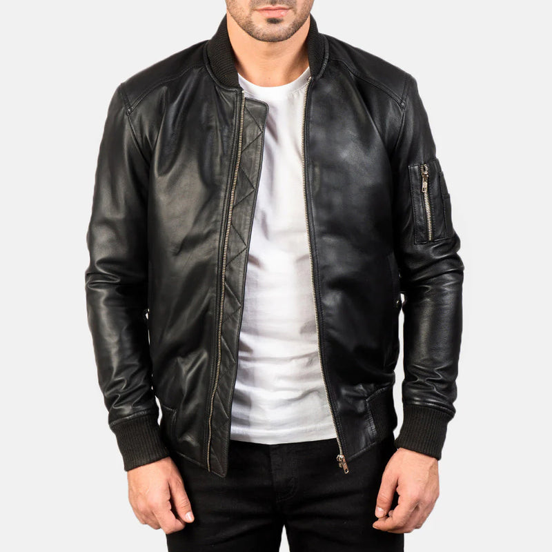 Front view of a man modeling an open black leather bomber jacket, showing the ribbed collar, cuffs, hem, and the iconic zippered arm pocket.