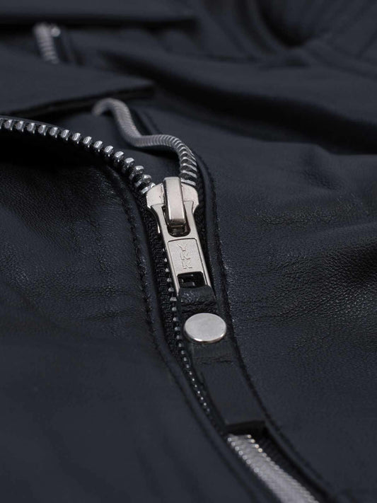 Front view of a tailored black leather moto jacket for women, showcasing the quilted shoulder detail, full zip, and snap-tab collar.