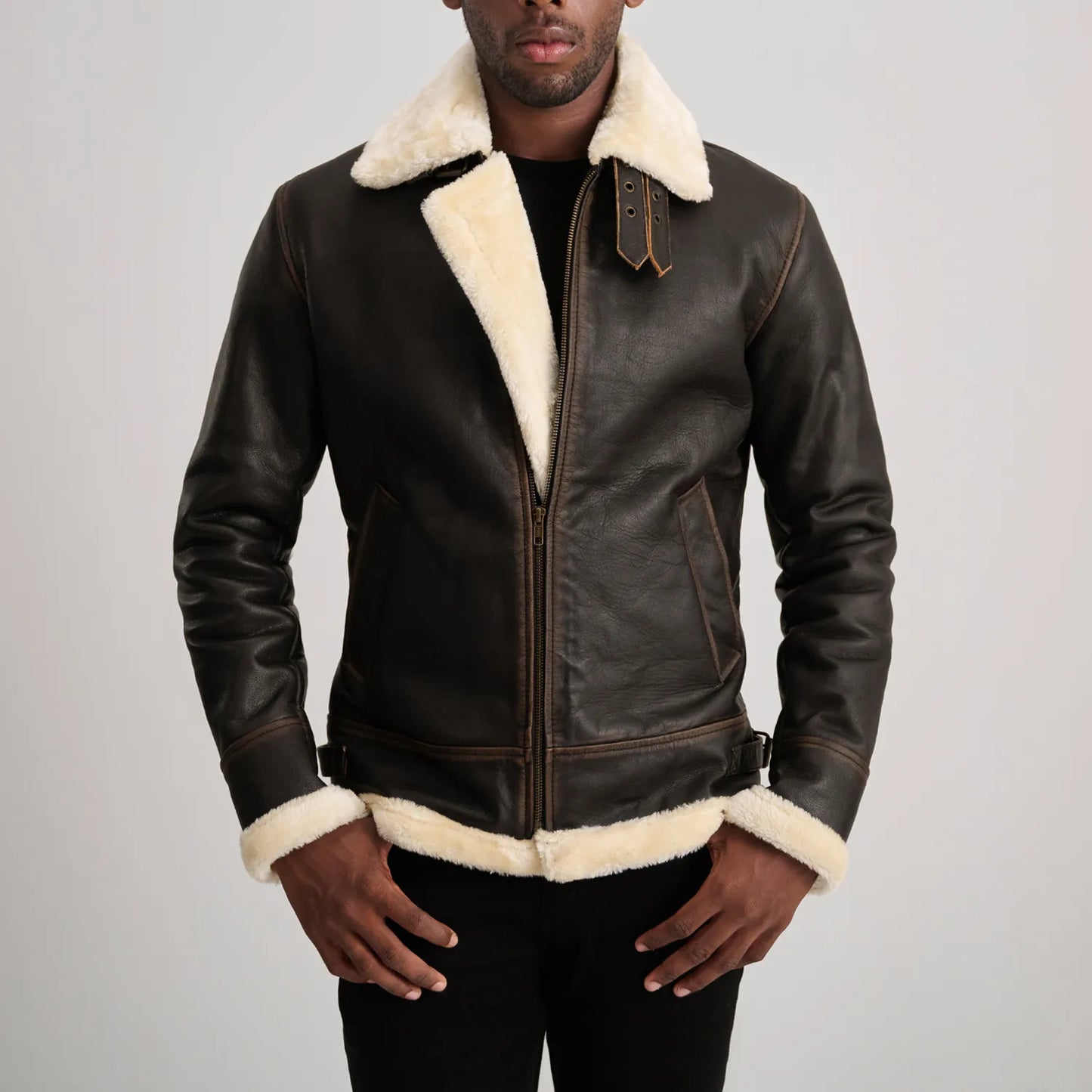 Back view of a man wearing a brown sheepskin leather jacket with thick white shearling visible at the collar, cuffs, and hem, highlighting the quality of the material.