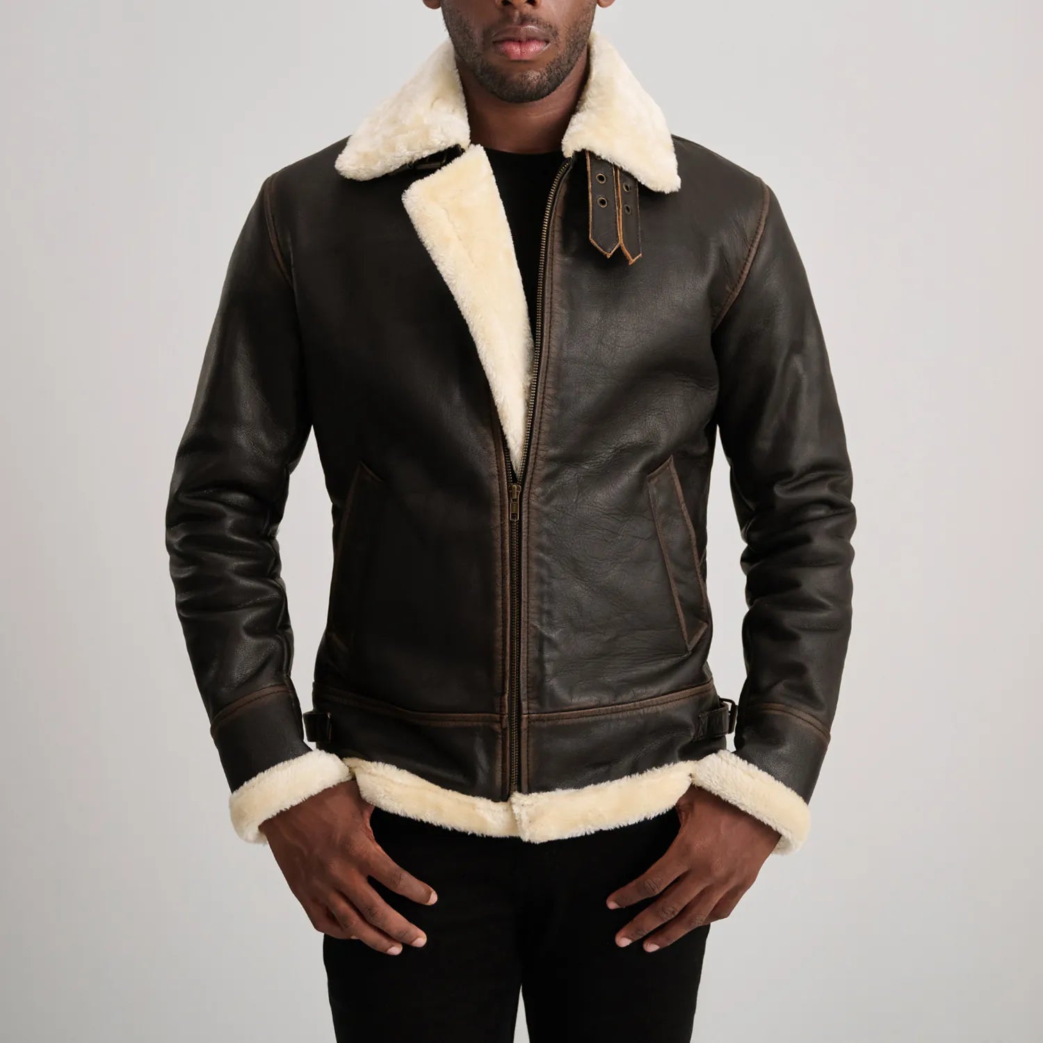 Back view of a man wearing a brown sheepskin leather jacket with thick white shearling visible at the collar, cuffs, and hem, highlighting the quality of the material.