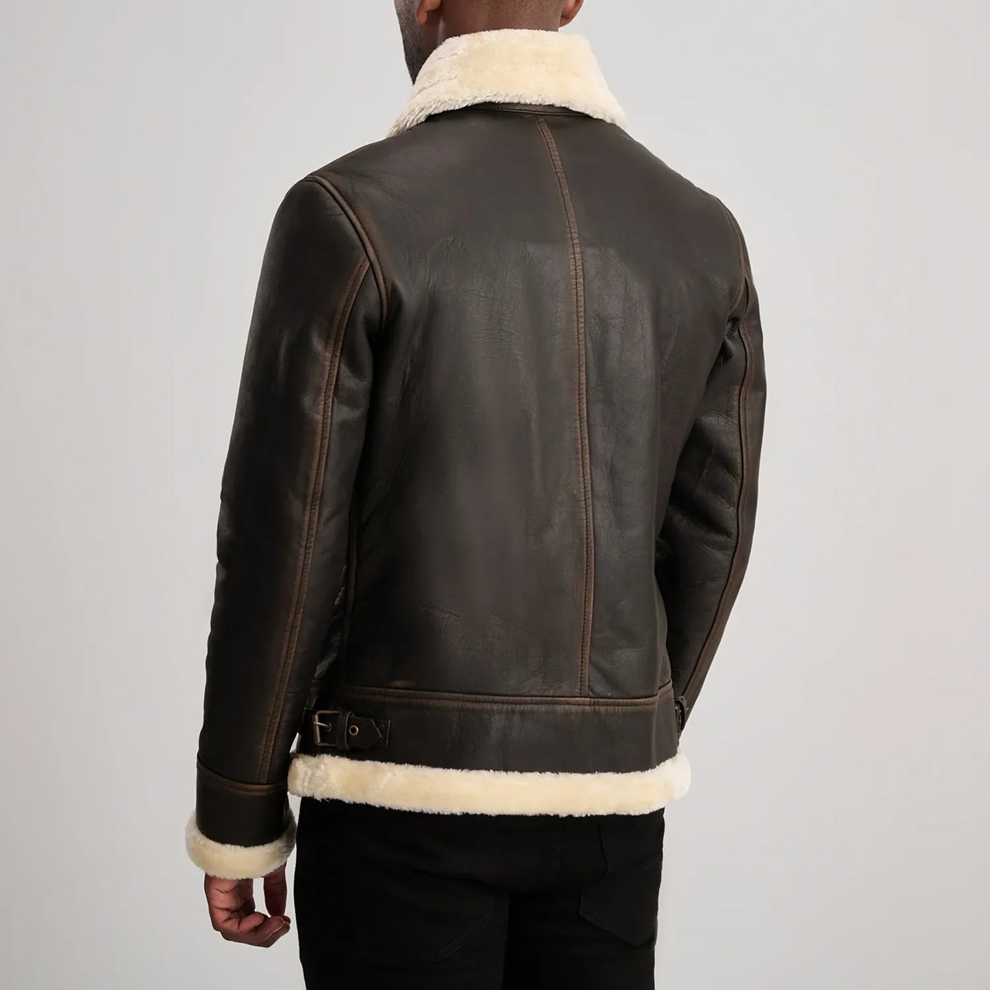 Back of a brown leather shearling jacket, detailing the vertical seam lines and the soft white wool trim along the bottom edge.
