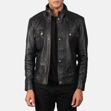 Front view of a man modeling a black leather jacket featuring two flap chest pockets, a snap-button front placket, and a buckle-fastening stand collar.