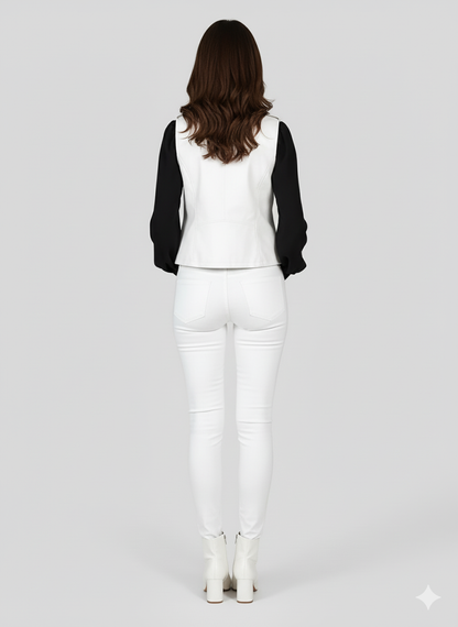 Sleeveless white leather jacket-style vest with a diagonal zip and pointed collar, paired with white ankle boots.