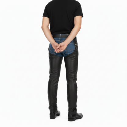 Male model wearing sleek black leather protective chaps with ankle cinches over blue jeans for a technical riding look.