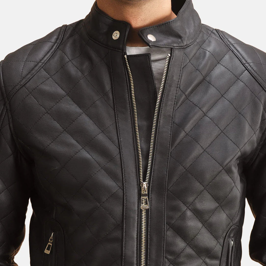 Front view of a man modeling a fully zipped black leather jacket, featuring diamond quilting and a small snap-button stand collar."
