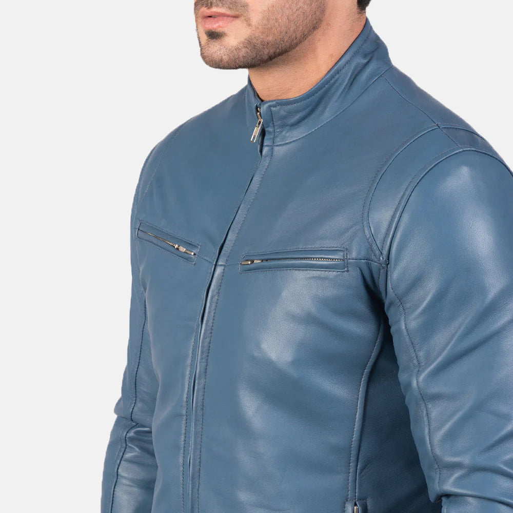 Front view of a man modeling an open steel blue leather jacket, showing the snap-button collar, horizontal zippered chest pockets, and a white t-shirt underneath.