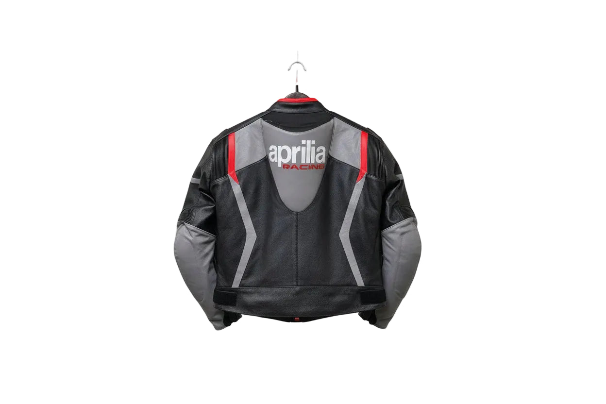 Detailed view of the Aprilia Racing chest logo, Akrapovič patch, and slate grey leather panels on a professional racing jacket.