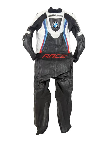 Detailed view of the BMW roundel, perforated leather cooling zones, and professional knee sliders on a racing suit.