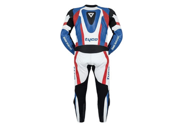 Detailed view of the BMW M roundel, Tyco sponsor patch, and perforated leather panels on a professional racing suit.