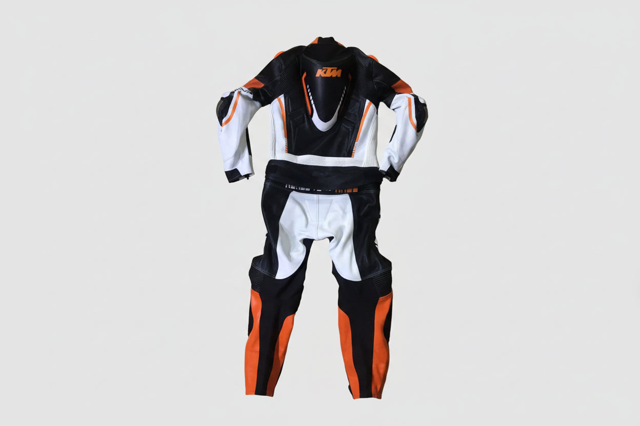 Detailed view of the KTM Ready to Race chest logo, Akrapovič patch, and orange accordion stretch panels on a professional racing suit.