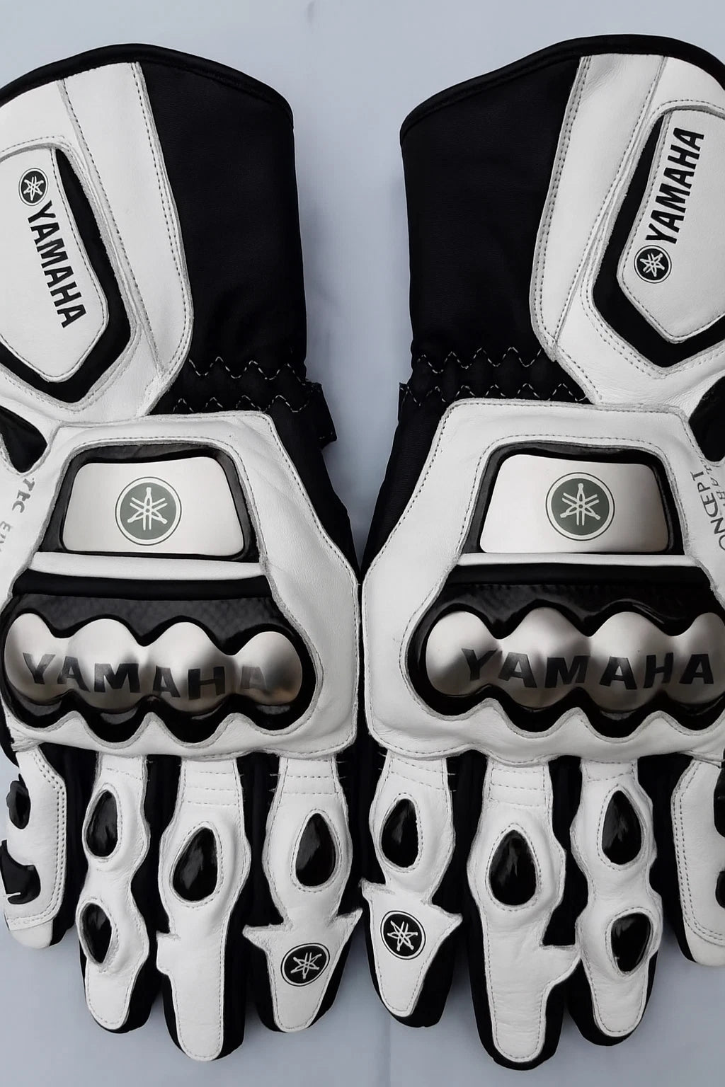 Yamaha leather motorcycle racing gloves in white and black with metallic knuckle armor.