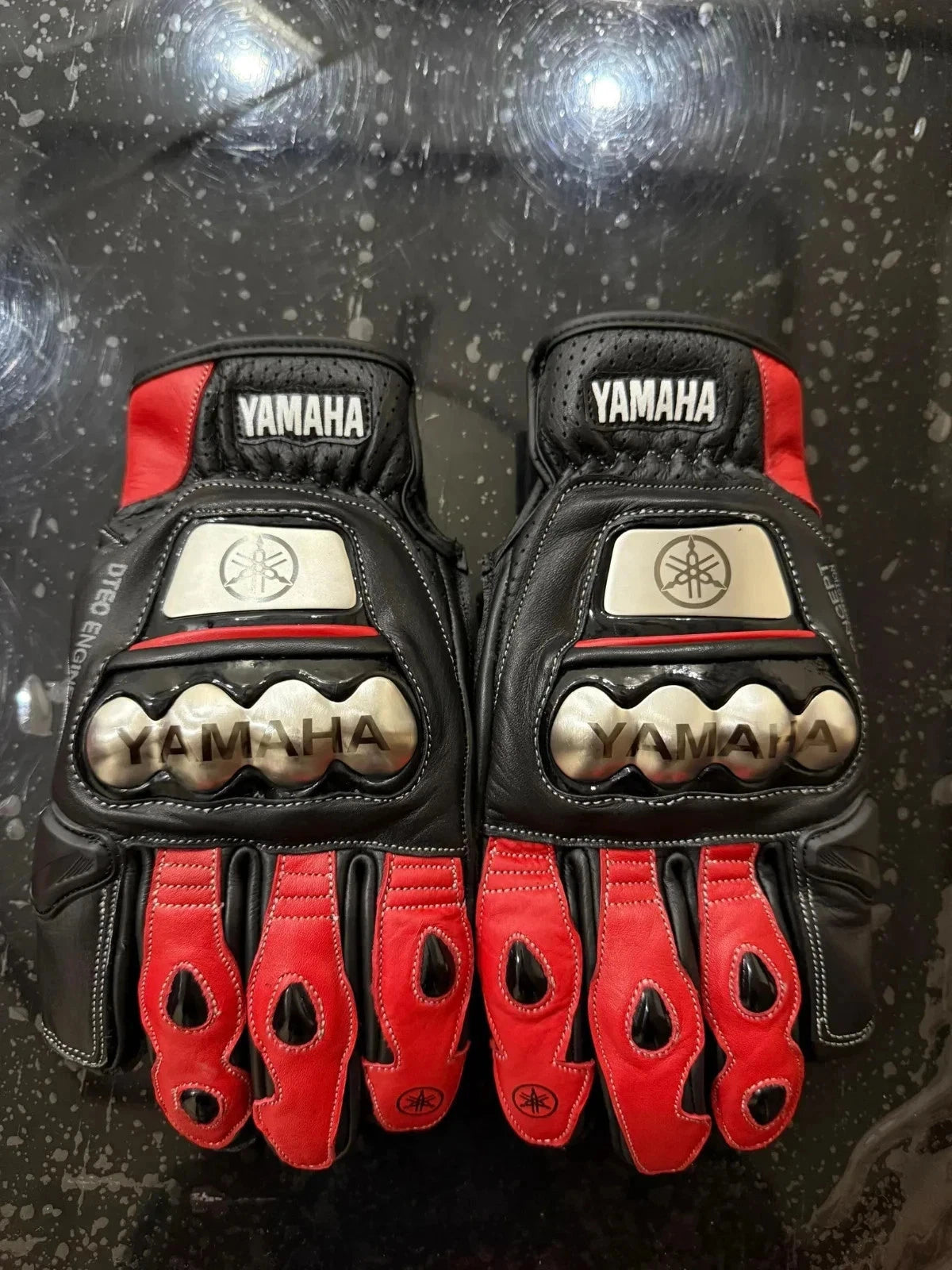 Yamaha factory leather motorcycle racing gloves in black and red with metallic knuckle armor.