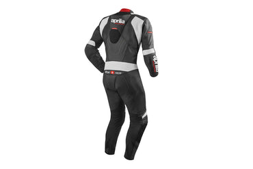 Detailed view of the Aprilia Racing chest logo, grey aerodynamic strikes, and red technical accents on a professional racing suit.